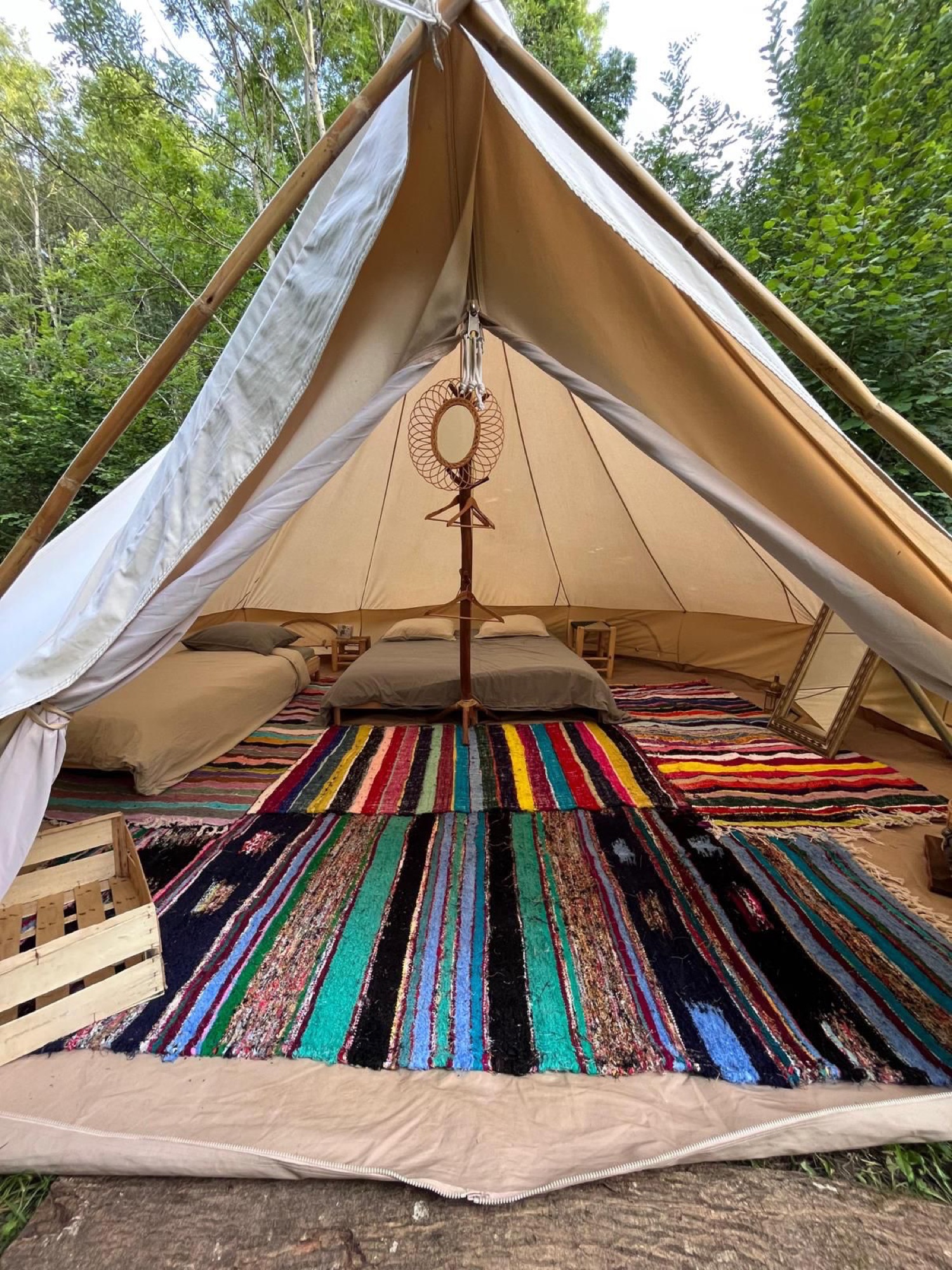 Une chambre sous tente avec plusieurs lits et des tapis colorés