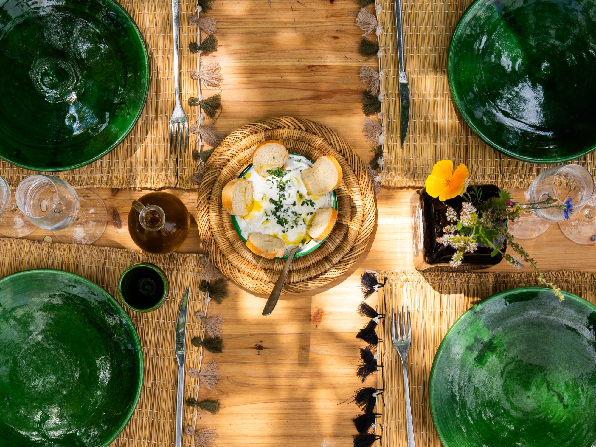 Une table dressée avec de la vaisselle verte et un plat à partager