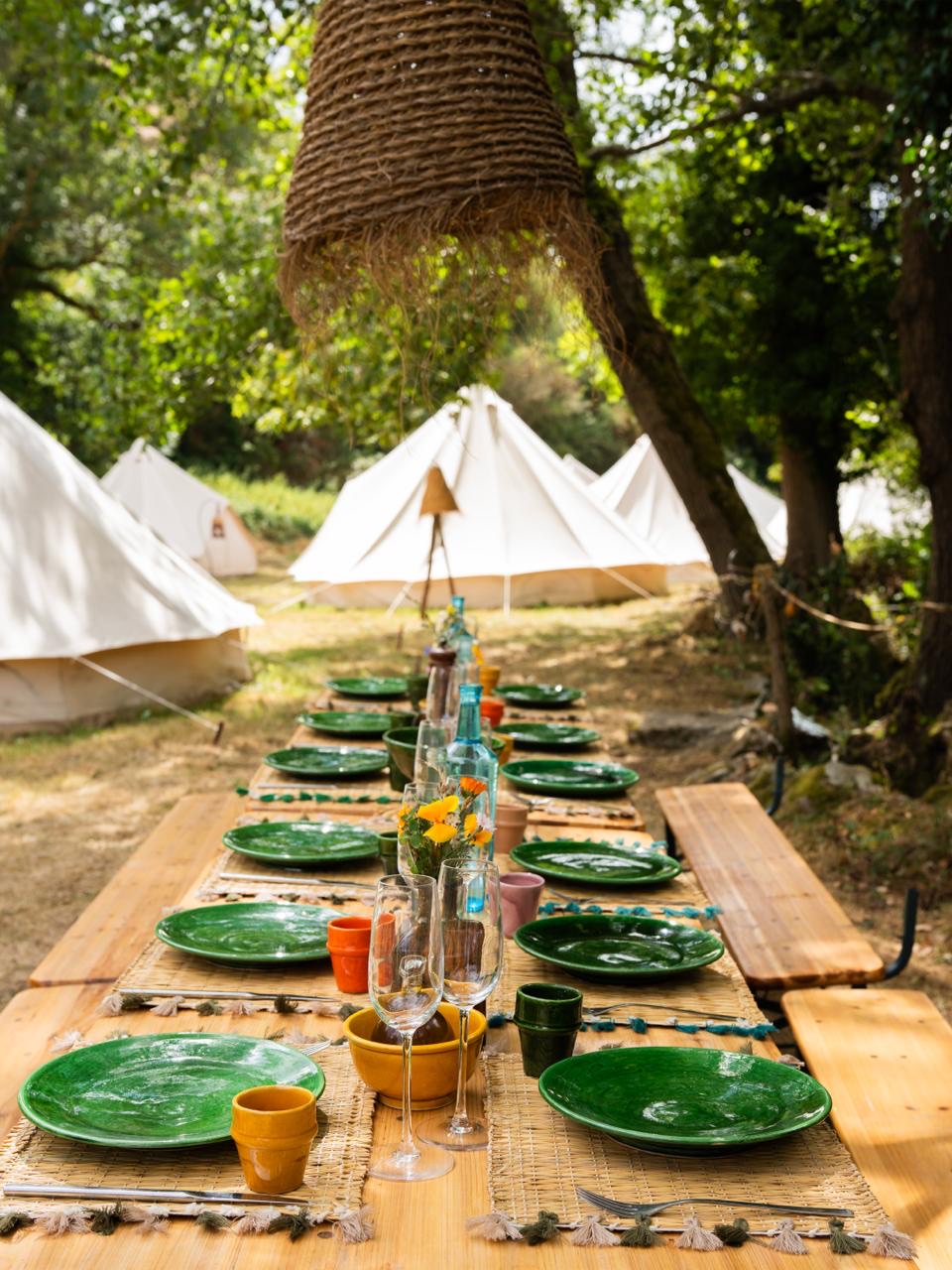 La grande table Mâ Hô dressée sous les arbres entre les tipis