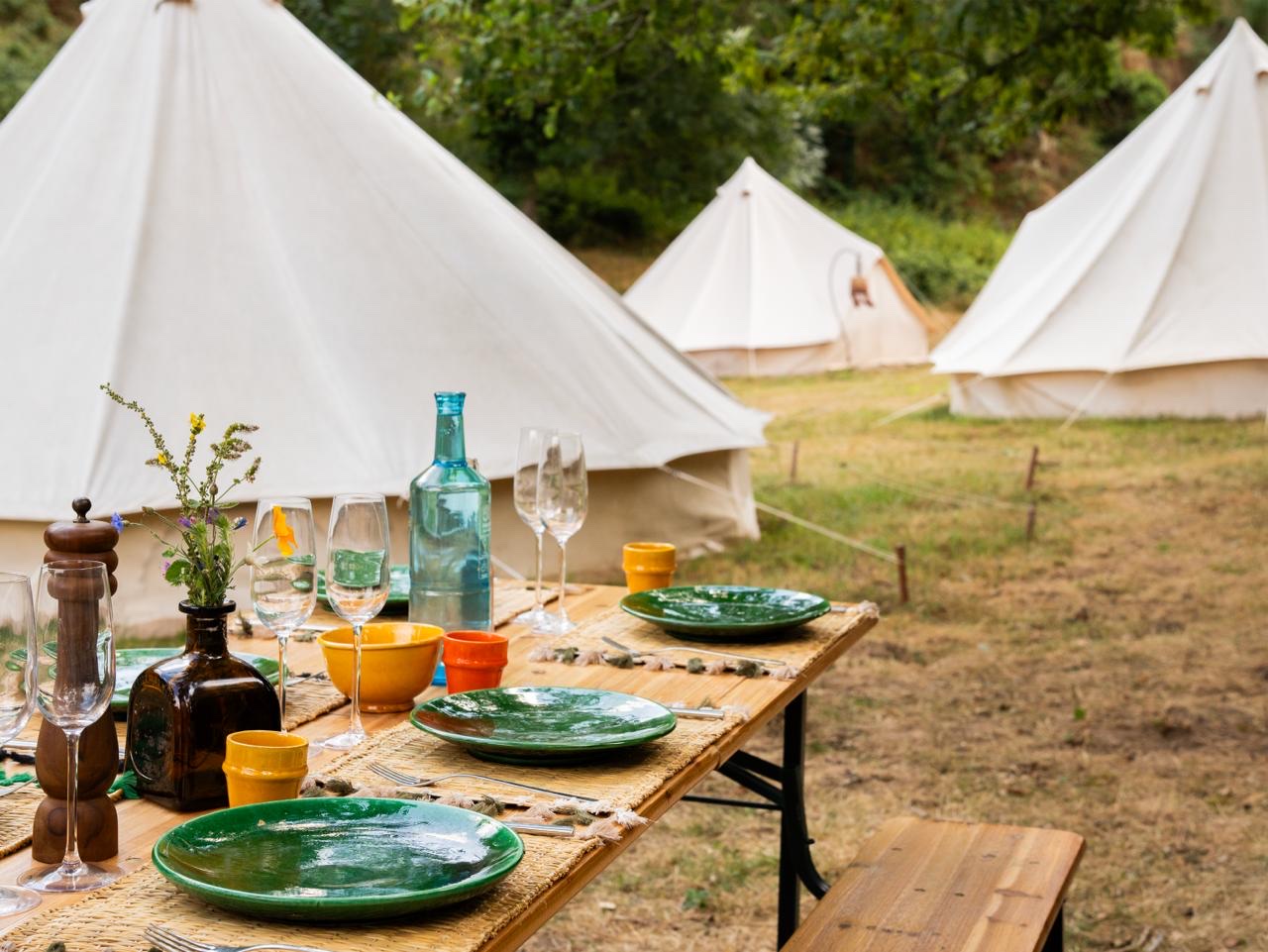 Une table dressée avec des assiettes vertes devant les tipis