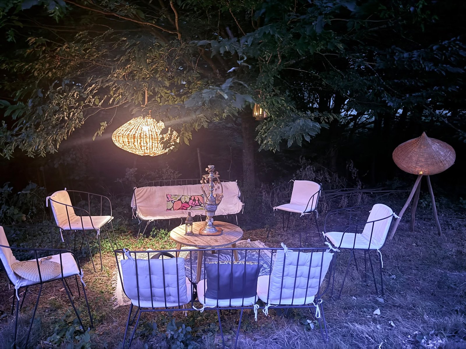 Un salon extérieur éclairé sous les arbres
