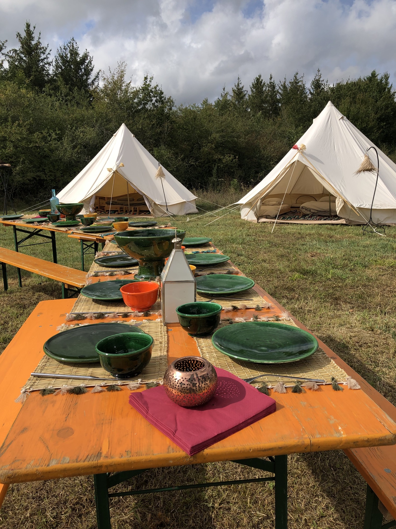 Une longue table colorée dressée devant les tentes